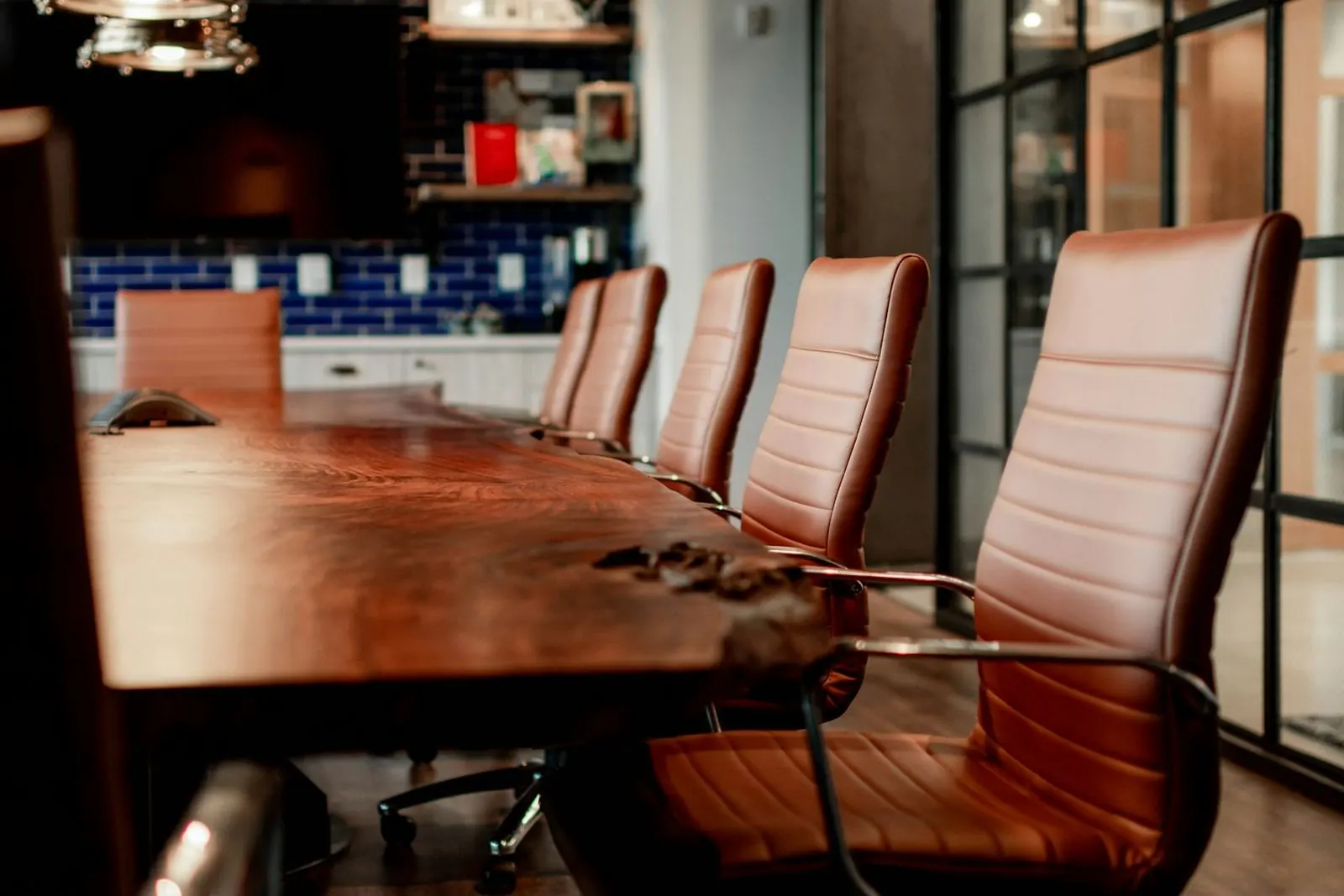 A meeting room with a long wooden table and leather chairs