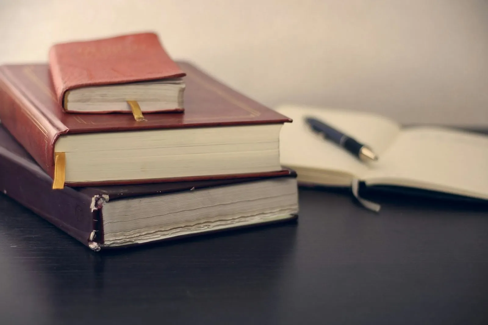 Books stacked next to an open notebook on a desk